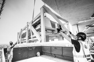 Construction workers holding onto a platform containing materials.