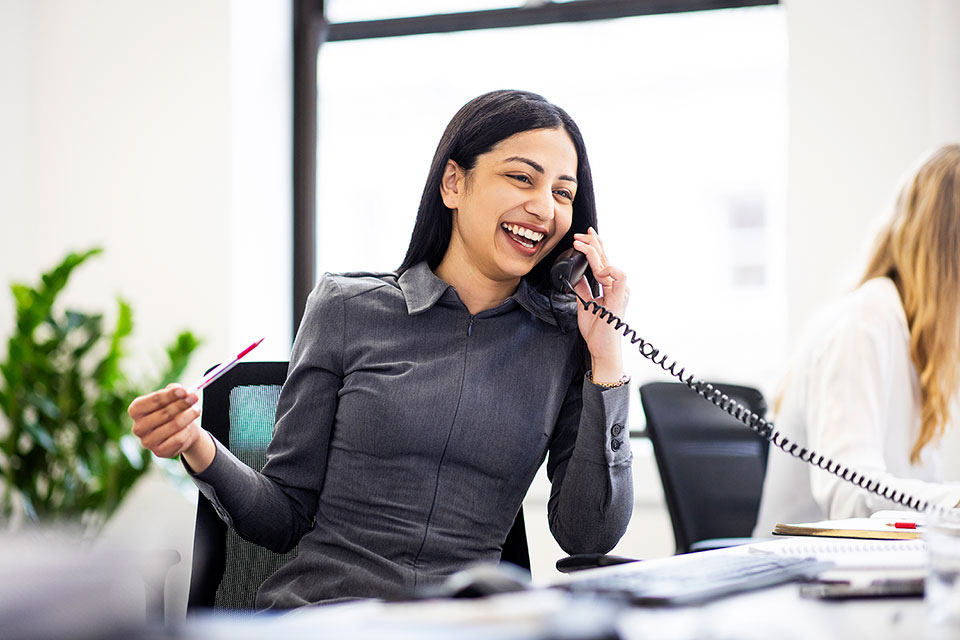 Corporate Lifestyle Photography for an annual report by Richard Boll. A woman at her desk having a relaxed conversation on the phone.