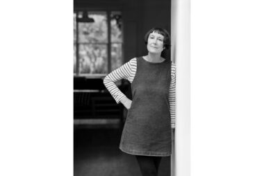 A black and white photographic portrait of the artist Cornelia Parker at her home in London.