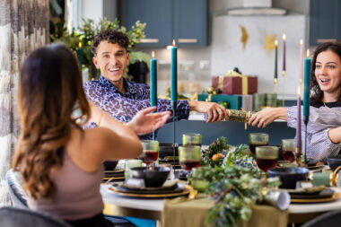 Friends pulling crackers at a Christmas dinner by lifestyle photographer Richard Boll.