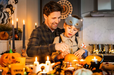 A lifestyle photograph of a father and son carving a pumpkin at Halloween.