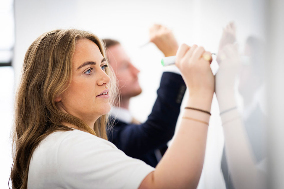 Corporate lifestyle photograph of a woman writing on a whiteboard by Richard Boll photography.